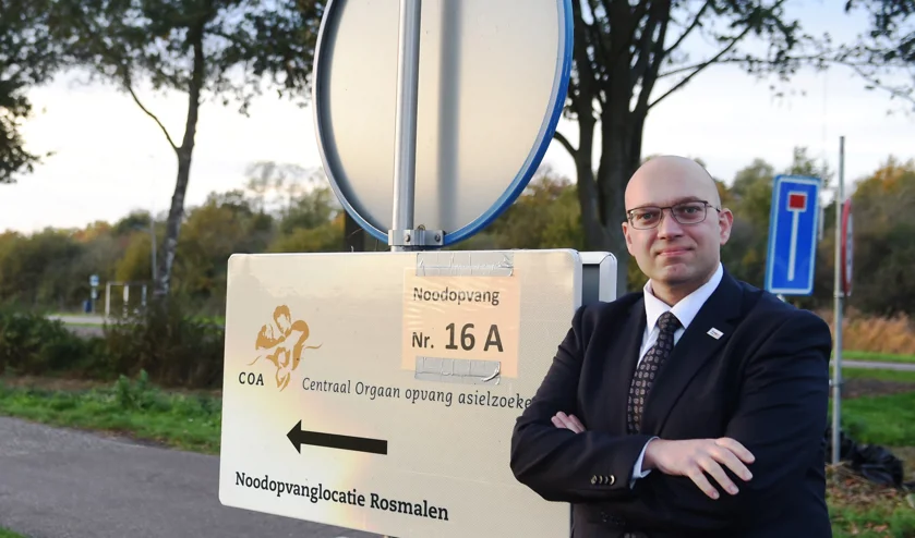 Foto van Alexander van Hattem die voor een bord staat met de tekst 'COA Noodopvanglocatie Rosmalen'