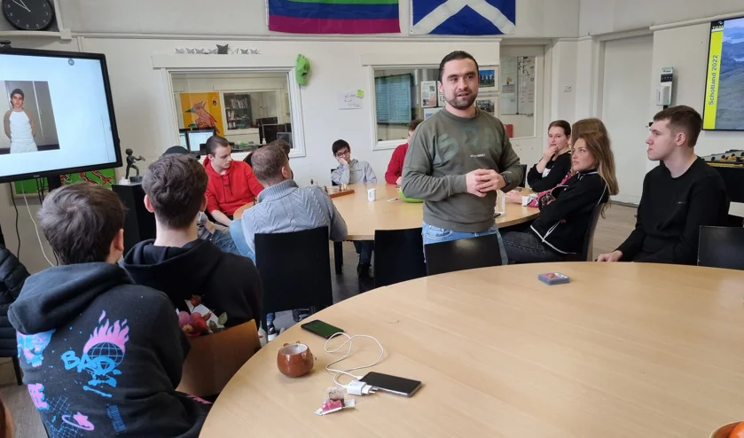 Foto van Osman Çifçi die in gesprek is met Bossche jongeren tijdens een bijeenkomst van T.O.M. (Traject op Maat)