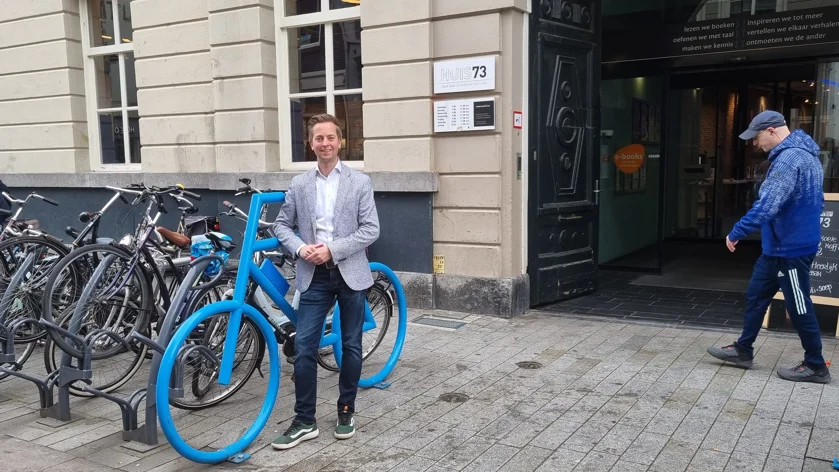 Foto van René van den Kerkhof die voor Huis73 staat bij de blauwe fiets